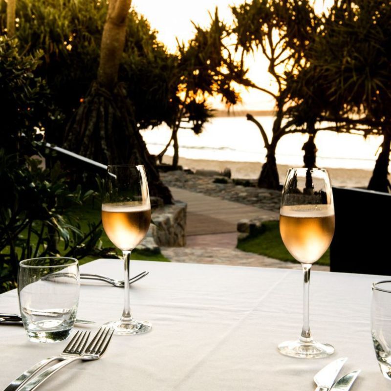 Romantic beachfront dining in Noosa with champagne and sunset views.